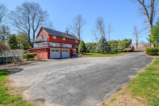 exterior space featuring an attached garage, driveway, and a chimney