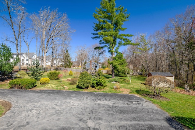 view of community featuring an outdoor structure, fence, and a yard