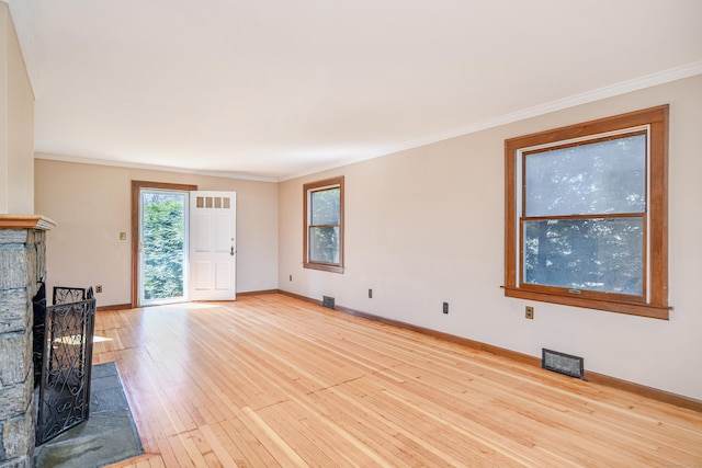 unfurnished living room with baseboards, visible vents, a fireplace with raised hearth, and light wood-style flooring