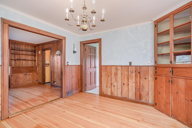 unfurnished room featuring wainscoting, visible vents, a chandelier, light wood-style floors, and ornamental molding