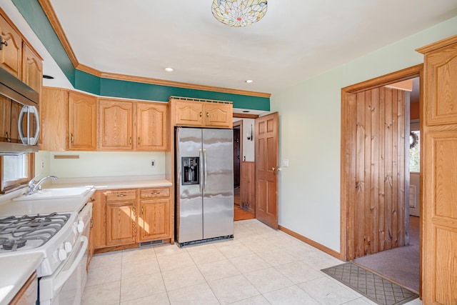 kitchen featuring light countertops, light tile patterned floors, a sink, baseboards, and appliances with stainless steel finishes
