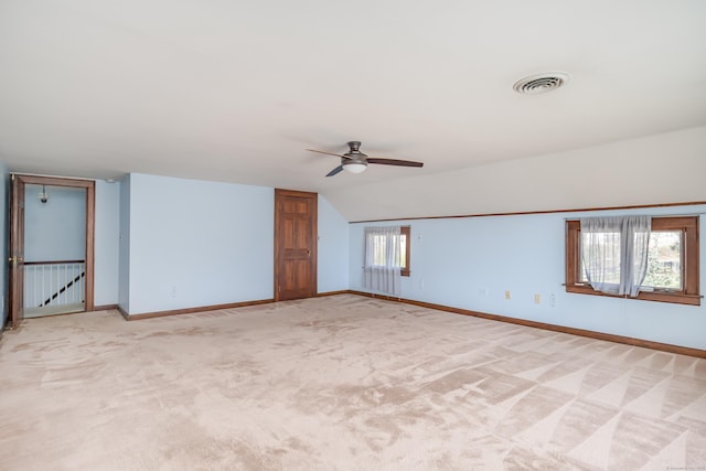 unfurnished room featuring light carpet, vaulted ceiling, visible vents, and ceiling fan