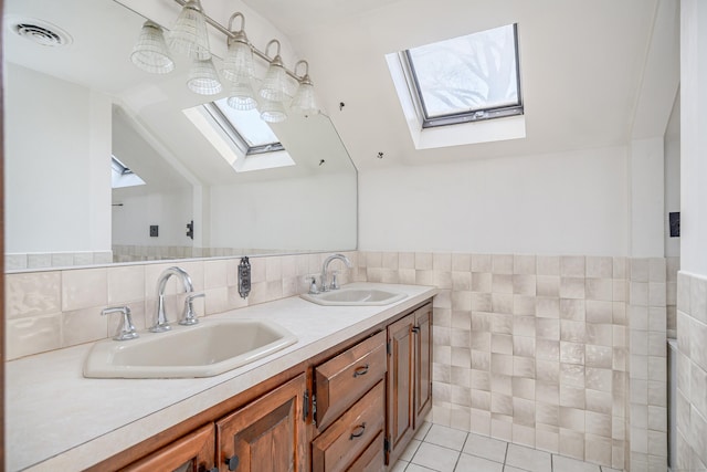 bathroom with lofted ceiling with skylight, a sink, visible vents, and tile walls