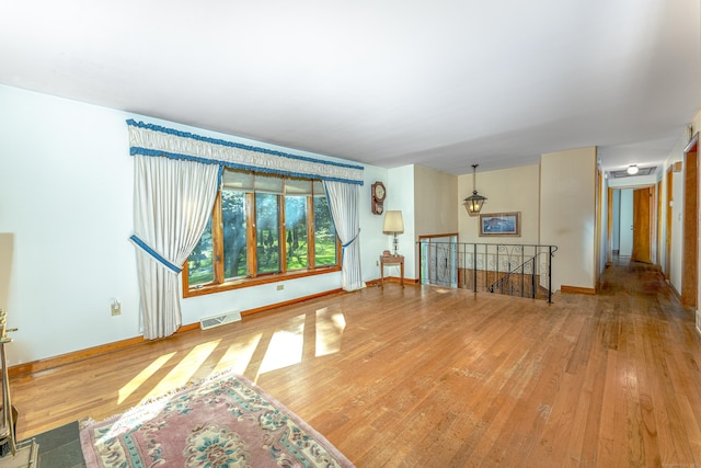 unfurnished living room with baseboards, wood finished floors, and visible vents