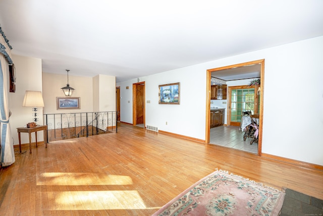 living room with baseboards, visible vents, and wood finished floors