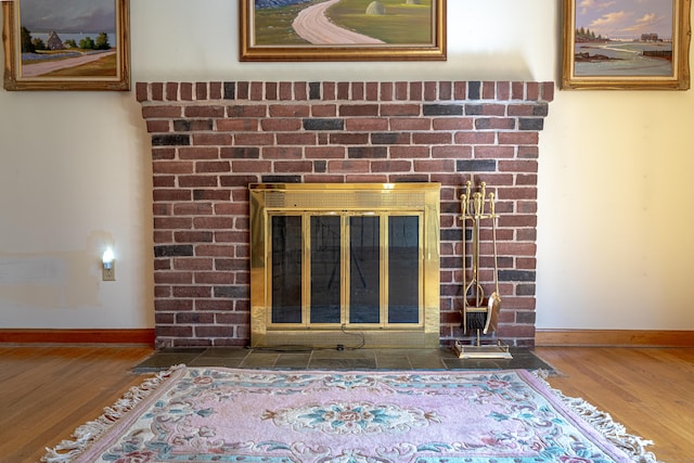 interior details featuring a brick fireplace, baseboards, and wood finished floors