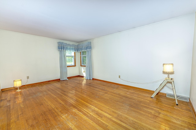 spare room featuring light wood-style floors, baseboards, and visible vents