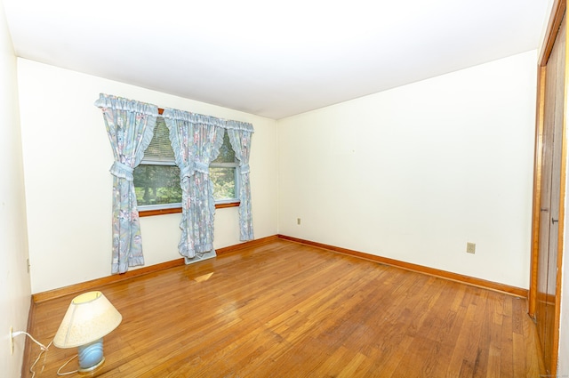 spare room with baseboards and wood finished floors