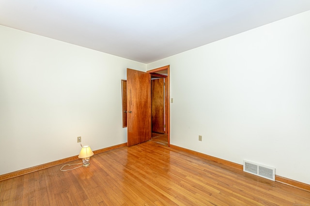 spare room with baseboards, light wood-style flooring, and visible vents