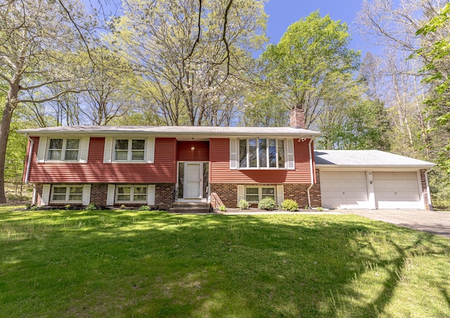 bi-level home with a front lawn, a chimney, brick siding, an attached garage, and driveway