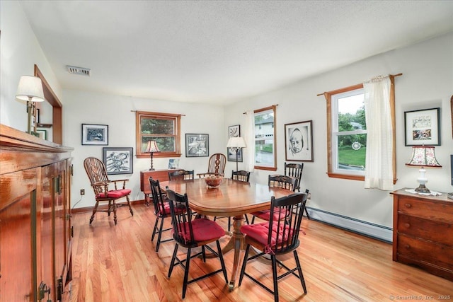 dining room with baseboard heating and light wood finished floors