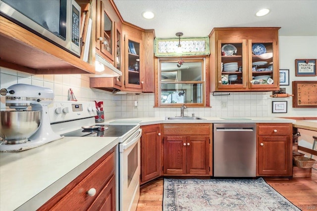 kitchen featuring appliances with stainless steel finishes, a sink, light countertops, light wood-type flooring, and recessed lighting