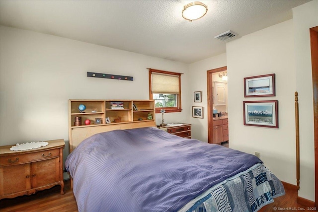 bedroom featuring wood finished floors and ensuite bath