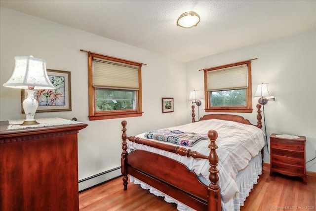 bedroom featuring baseboard heating, wood finished floors, and multiple windows