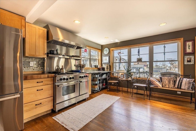 kitchen with wall chimney range hood, tasteful backsplash, stainless steel appliances, recessed lighting, and dark wood finished floors