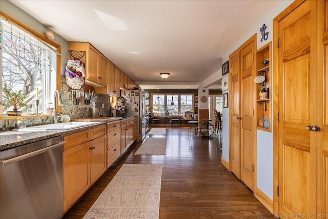 kitchen featuring dark wood finished floors, decorative backsplash, dishwasher, a sink, and open floor plan