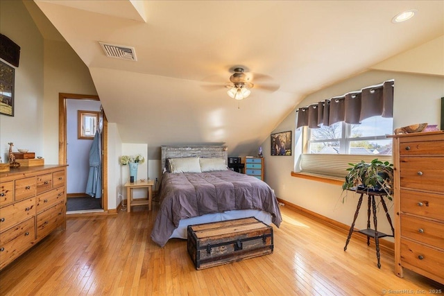 bedroom featuring baseboards, visible vents, hardwood / wood-style flooring, and vaulted ceiling