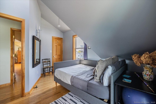 bedroom featuring baseboards, vaulted ceiling, and light wood-type flooring