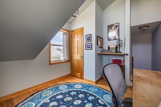 home office featuring baseboards, light wood-style floors, and lofted ceiling