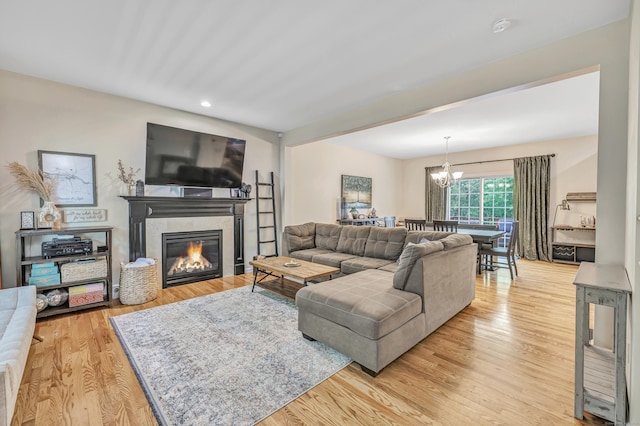 living room featuring a tile fireplace, a chandelier, recessed lighting, and light wood-type flooring