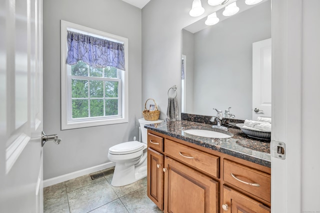 half bathroom featuring toilet, vanity, baseboards, and tile patterned floors
