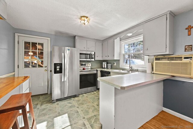 20 Sims Rd, Bristol, CT 06010 - kitchen featuring light countertops, a sink, a peninsula, a wall mounted AC, and appliances with stainless steel finishes