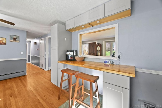 20 Sims Rd, Bristol, CT 06010 - kitchen with white cabinets, wooden counters, a baseboard radiator, light wood-style flooring, and a textured ceiling