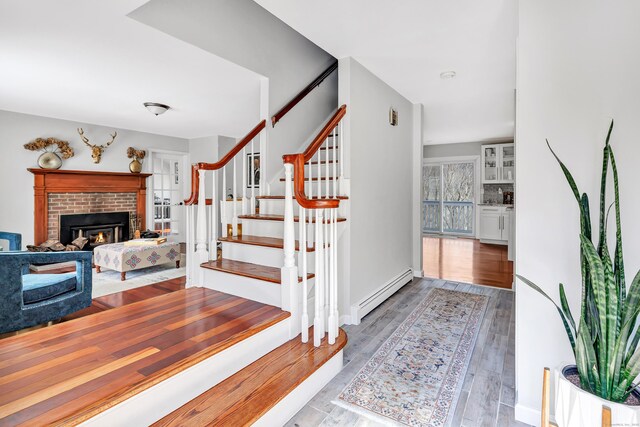 190 Thoreau Dr, Shelton, CT 06484 - stairway with baseboard heating, a brick fireplace, and wood finished floors