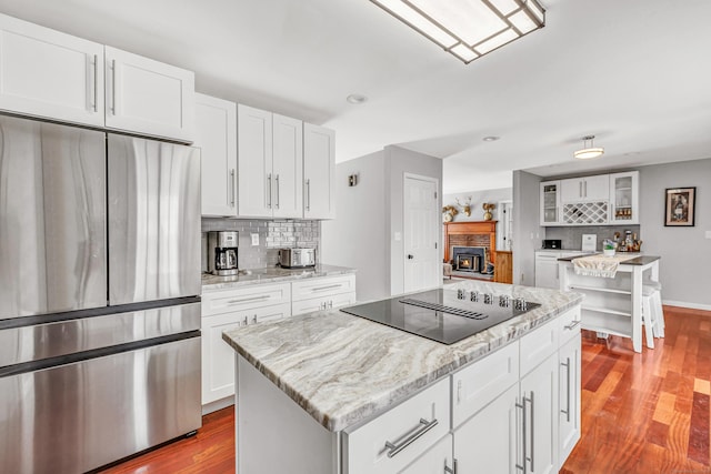 190 Thoreau Dr, Shelton, CT 06484 - kitchen with black electric cooktop, wood finished floors, stainless steel refrigerator, and tasteful backsplash