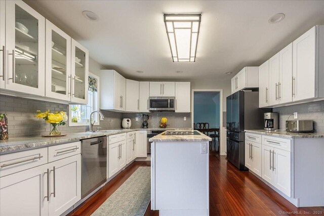 190 Thoreau Dr, Shelton, CT 06484 - kitchen with appliances with stainless steel finishes, decorative backsplash, white cabinetry, dark wood-style floors, and glass insert cabinets