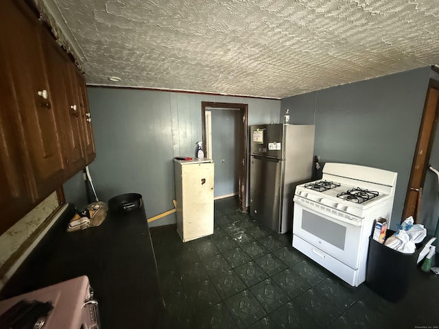 148 Plymouth St, New Haven, CT 06519 - kitchen featuring dark floors, freestanding refrigerator, a textured ceiling, and gas range gas stove