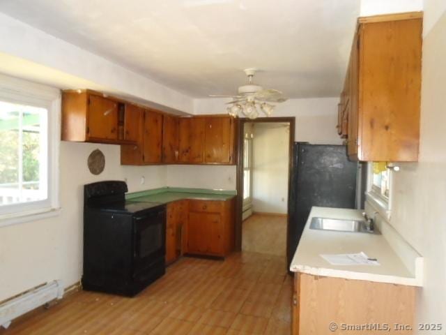 35 Greenhouse Blvd, West Hartford, CT 06110 - kitchen with stove, brown cabinets, light countertops, a sink, and baseboard heating