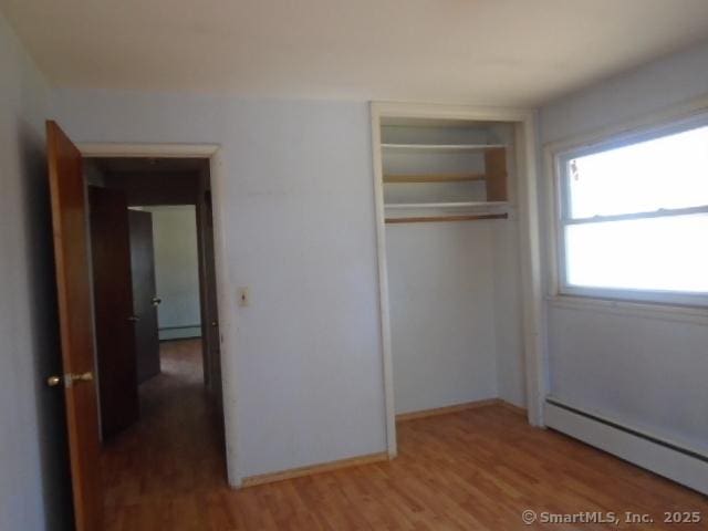 35 Greenhouse Blvd, West Hartford, CT 06110 - unfurnished bedroom with baseboard heating, wood finished floors, a closet, and a baseboard radiator