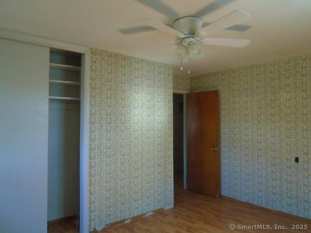 35 Greenhouse Blvd, West Hartford, CT 06110 - unfurnished bedroom with a ceiling fan, wood finished floors, wallpapered walls, and a closet