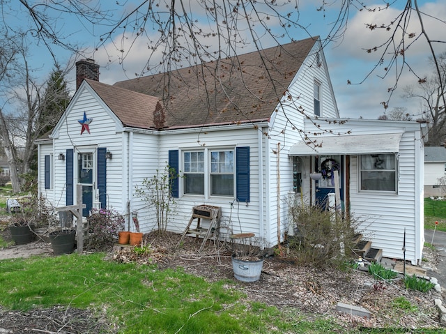 view of front of house featuring a chimney and roof with shingles