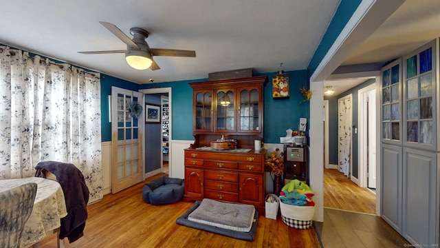 bedroom featuring a wainscoted wall, wood finished floors, and a ceiling fan