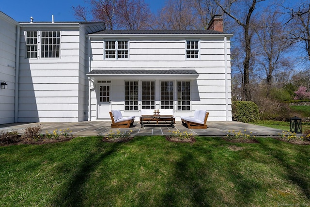 back of house featuring outdoor lounge area, a chimney, a yard, and a patio