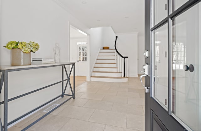 entrance foyer featuring crown molding, stairs, and light tile patterned floors
