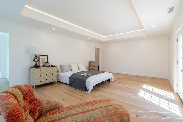 bedroom featuring crown molding, light wood-style flooring, visible vents, a tray ceiling, and baseboards