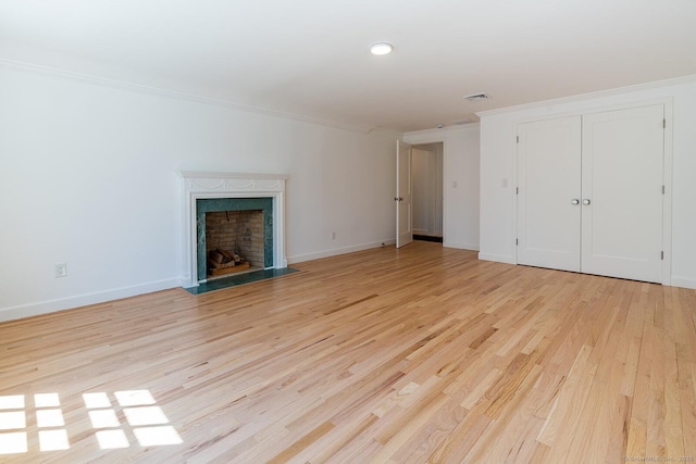 unfurnished living room with a fireplace, light wood-style floors, ornamental molding, and baseboards