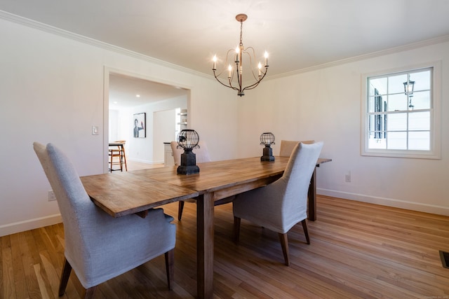 dining room with light wood-style floors, crown molding, a notable chandelier, and baseboards