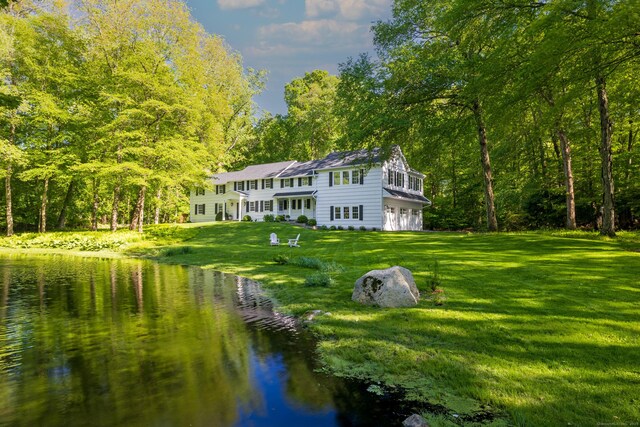 148 W Hills Rd, New Canaan, CT 06840 - back of house featuring a water view, an attached garage, a lawn, and a wooded view