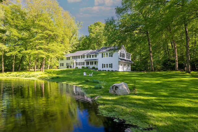 148 W Hills Rd, New Canaan, CT 06840 - rear view of property with a water view, an attached garage, a lawn, and a view of trees
