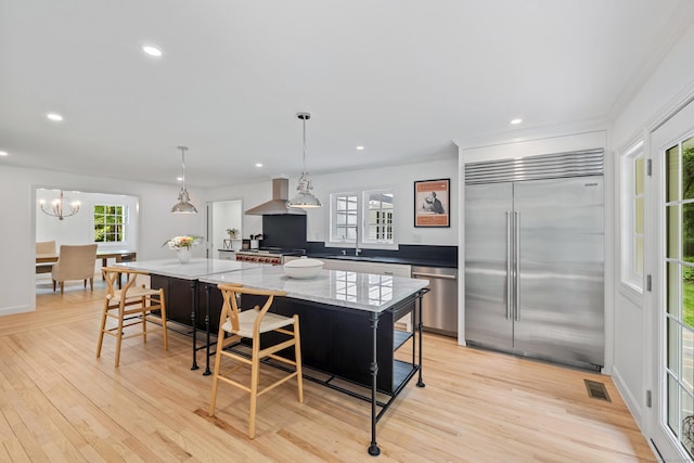 148 W Hills Rd, New Canaan, CT 06840 - kitchen with stainless steel appliances, light wood-style flooring, a large island, wall chimney exhaust hood, and recessed lighting