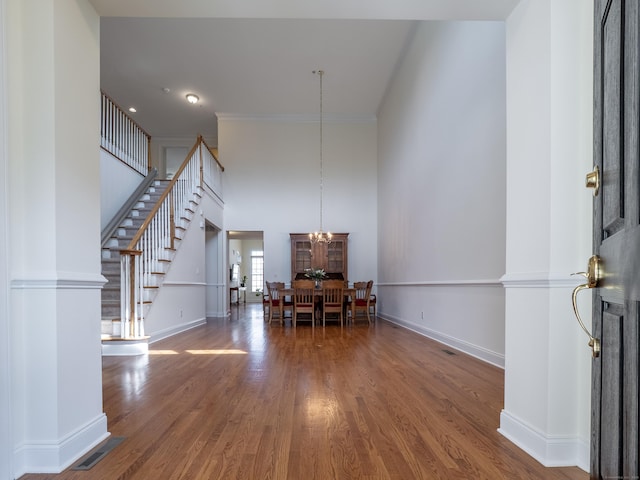 entryway featuring crown molding, stairway, visible vents, baseboards, and wood finished floors