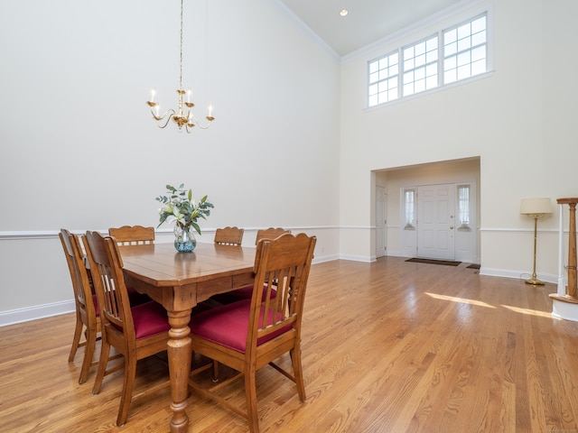 dining space with baseboards, high vaulted ceiling, a notable chandelier, and light wood finished floors