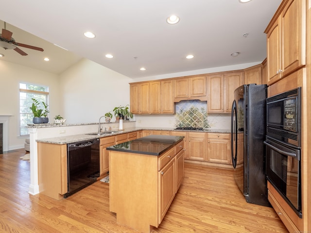 kitchen featuring recessed lighting, black appliances, light wood finished floors, a sink, and a peninsula