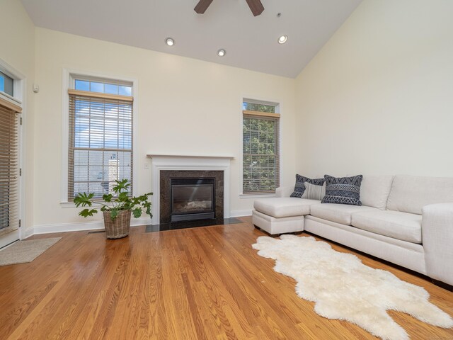 living area with ceiling fan, plenty of natural light, a fireplace with flush hearth, and vaulted ceiling