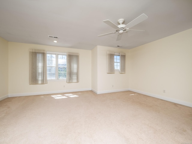 empty room with light colored carpet, visible vents, ceiling fan, and baseboards