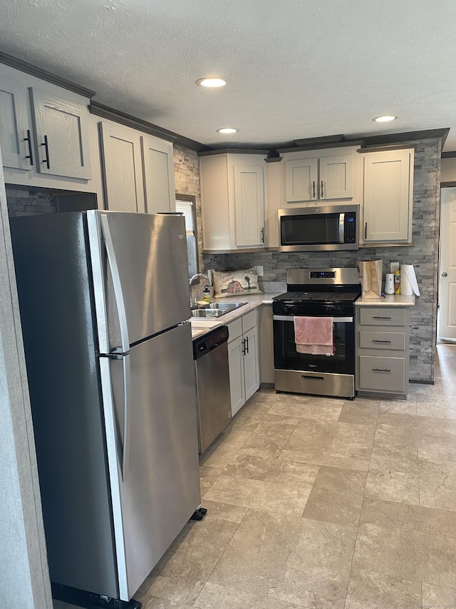 kitchen with a textured ceiling, a sink, stainless steel appliances, light countertops, and gray cabinets